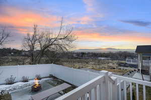 Balcony at dusk featuring a fire pit and a patio