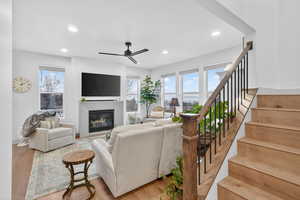 Living room featuring a ceiling fan, light wood finished floors, recessed lighting, and a glass covered fireplace