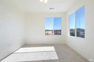 Spare room featuring light colored carpet and baseboards