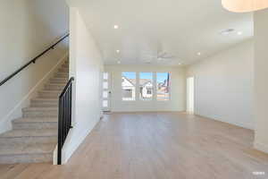 Unfurnished living room featuring light wood-type flooring, stairs, recessed lighting, and a ceiling fan