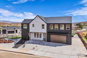 View of front of home with a mountain view, a metal roof, an attached garage, stucco siding, and concrete driveway