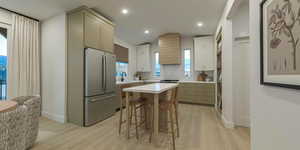 Two tone kitchen featuring freestanding refrigerator, light wood finished floors, a breakfast bar, two tone color scheme, and tasteful backsplash