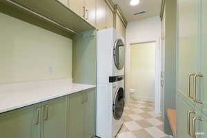 Laundry area featuring light flooring, stacked washer / drying machine, and cabinet space
