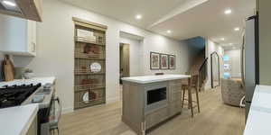 Kitchen featuring stainless steel appliances, light wood-style flooring, a center island, extractor fan, and recessed lighting