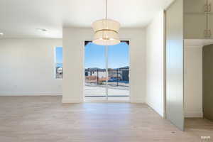 Unfurnished dining area with light wood-style flooring and baseboards