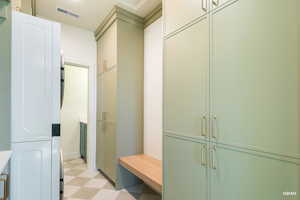 Mudroom with light flooring and stacked washer / drying machine