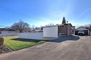 View of property exterior featuring brick siding, a detached garage, and an outbuilding