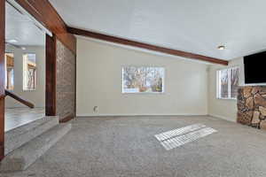 Unfurnished living room featuring beamed ceiling and carpet floors