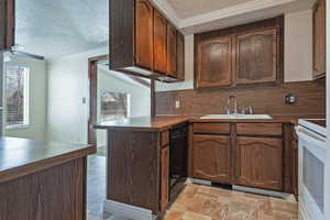 Kitchen featuring white range, decorative backsplash, a textured ceiling, a peninsula, and stone finish floors
