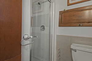 Bathroom with a stall shower, tile walls, and a wainscoted wall