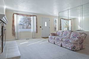Tiled living room with carpet flooring, a textured ceiling, and ornamental molding