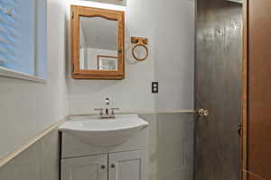 Bathroom with vanity, a textured ceiling, tile walls, and wainscoting