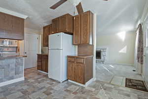 Kitchen featuring ornamental molding, white appliances, a ceiling fan, a textured ceiling, and a fireplace
