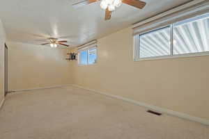 Empty room featuring a ceiling fan, a textured ceiling, and speckled floor