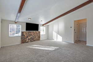Unfurnished living room with beamed ceiling and carpet floors