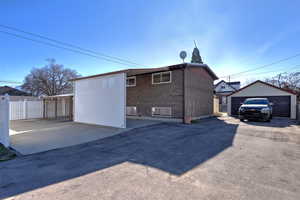 Rear view of property featuring brick siding, a detached garage, and an outbuilding