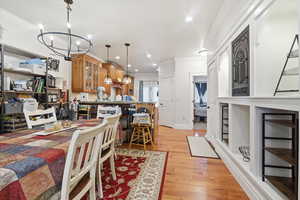 Dining room with ornamental molding, light wood-style floors, and hanging lights