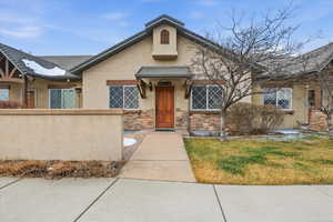 View of front of property featuring stucco siding, stone siding, and a front lawn