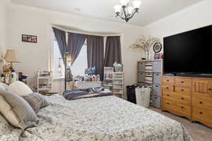 Bedroom featuring light colored carpet, suspended lighting, and crown molding