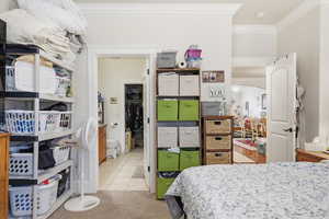 Bedroom with arched walkways, crown molding, and light carpet