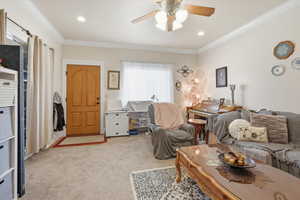 Living area with crown molding, light colored carpet, ceiling fan, and recessed lighting