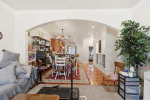 Living area featuring arched walkways, light wood-style flooring, crown molding, and a chandelier
