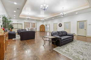 Living room featuring a raised ceiling and a chandelier