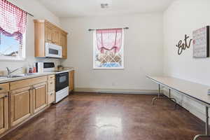 Kitchen featuring electric stove, concrete flooring, light countertops, white microwave, and a baseboard heating unit