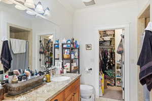 Full bath with a walk in closet, crown molding, curtained shower, and vanity