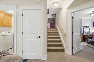 Staircase with washer and dryer, carpet floors, and ornamental molding