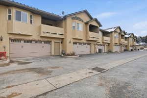 Rear view of house with stucco siding, an attached garage, and a residential view