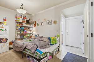 Bedroom featuring freestanding refrigerator, crown molding, and light tile patterned floors