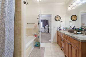 Bathroom with crown molding, double vanity, a garden tub, light tile patterned floors, and curtained shower
