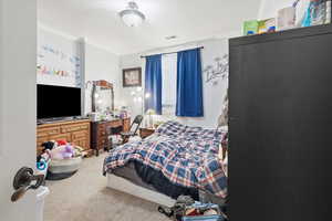 Bedroom with light colored carpet and crown molding