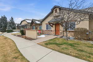 View of front facade featuring stucco siding, a front lawn, and stone siding