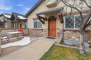 Doorway to property with stone siding and stucco siding