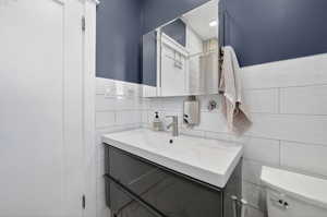 Bathroom with tile walls, vanity, and a shower with curtain
