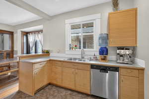 Kitchen with stainless steel dishwasher, light countertops, plenty of natural light, a peninsula, and beam ceiling