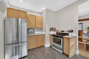 Kitchen featuring freestanding refrigerator, electric stove, recessed lighting, and tile countertops