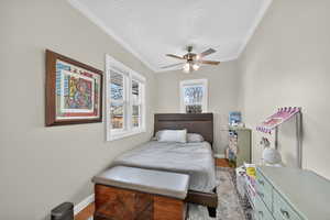 Second Bedroom with wood finished floors, ornamental molding, and ceiling fan