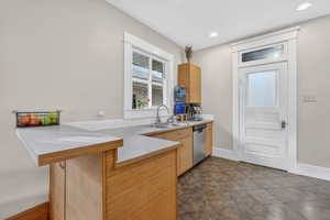Kitchen featuring a peninsula, light countertops, a kitchen breakfast bar, and stainless steel dishwasher