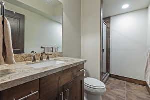 Full bathroom with vanity, a shower stall, recessed lighting, and dark tile patterned floors