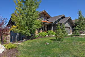 View of front of house with board and batten siding, stone siding, a front lawn, and a shingled roof