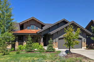 Craftsman house featuring stone siding, driveway, a garage, and board and batten siding