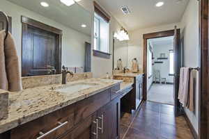 Bathroom with two vanities, recessed lighting, and dark tile patterned flooring