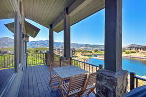 Wooden deck featuring outdoor dining space and a water and mountain view