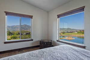 Bedroom featuring hardwood / wood-style flooring, a water and mountain view, and lofted ceiling