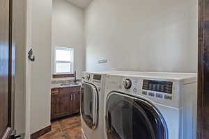 Washroom with dark tile patterned flooring and washer and dryer