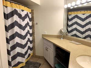 Bathroom with vanity, a shower with shower curtain, and light tile patterned flooring