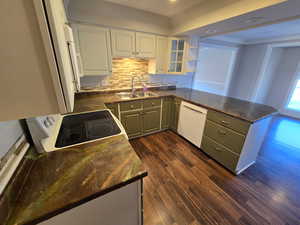 Kitchen featuring two tone cabinetry, dark wood-style floors, a peninsula, white appliances, and open shelves